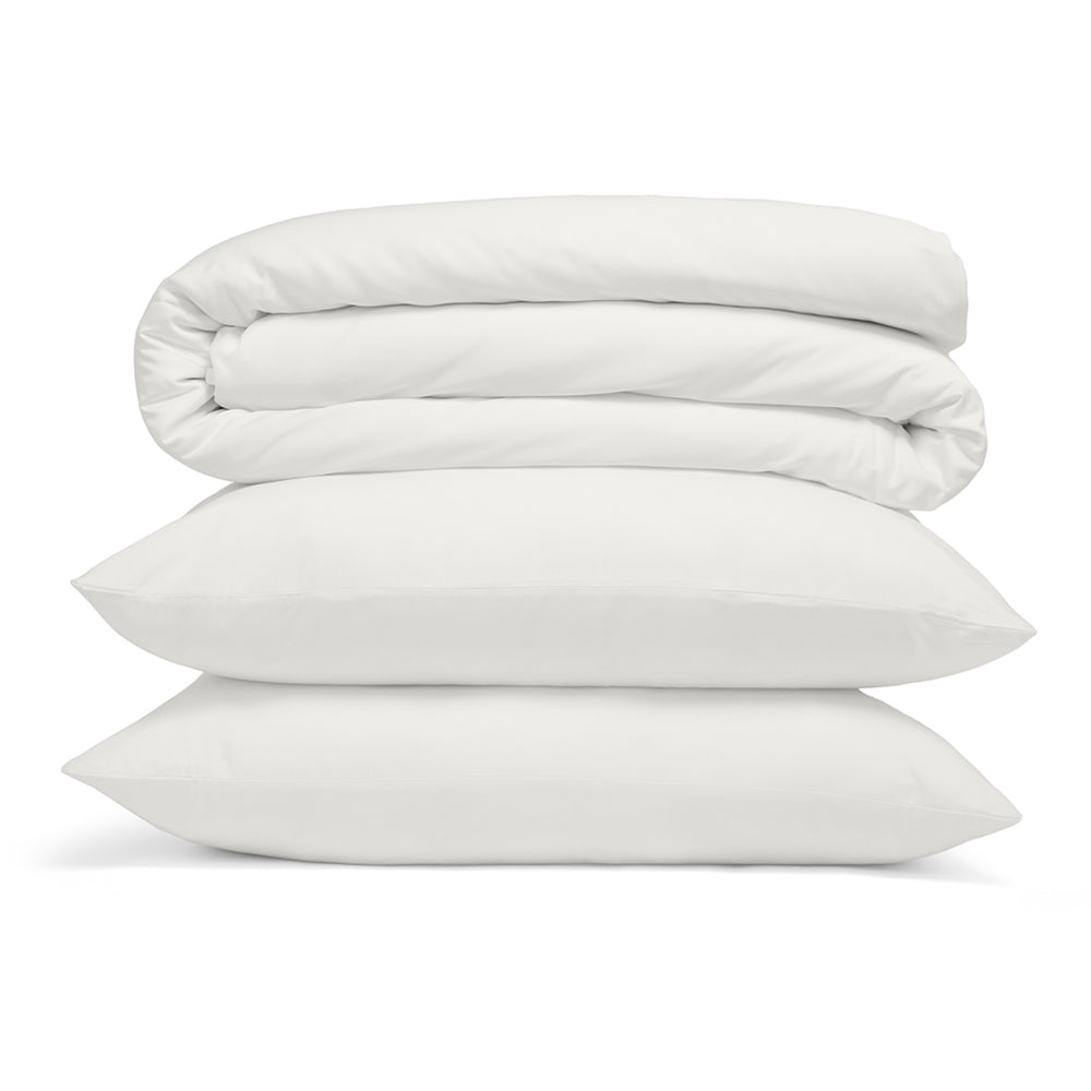 Pile d’ensembles de couette avec taie d’oreiller sur fond blanc – literie moderne, tissus de haute qualité, luxueuse et confortable
